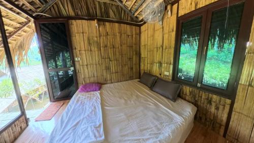 a bed in a small room with windows at Pu Luong Roots Homestay in Pu Luong