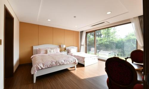 a bedroom with a bed and a large window at Jeju Tameus Golf & Village in Hahwajŏn