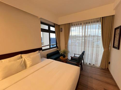a hotel room with a bed and a chair and a window at TimeOut Dalat Boutique Hotel in Khu Chi Lăng