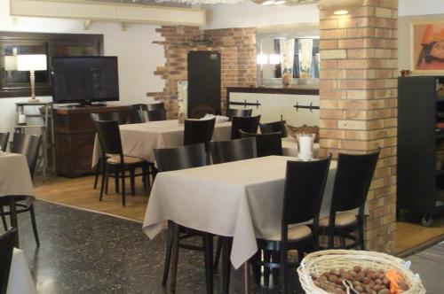 a dining room with tables and chairs and a tv at Hôtel U Pozzu in Sisco