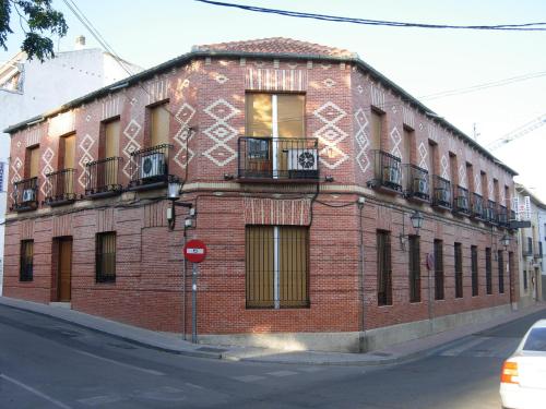 um edifício de tijolos vermelhos com uma varanda numa rua em Hostal Cervantes em Valdemoro