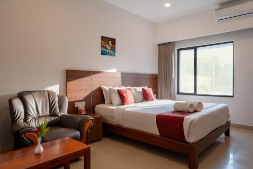 a hotel room with a bed and a chair at Hotel Sandra Palace in Thekkady