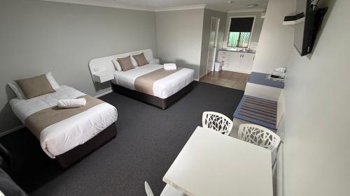 a small room with two beds and a table and chairs at Jefferys Motel in Toowoomba