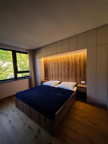 a bedroom with a large bed and a wooden wall at Apartmán Vyhne in Vyhne