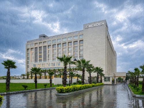 a large building with palm trees in front of it at Le Meridien Amritsar in Amritsar