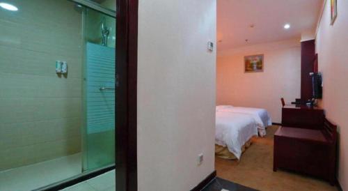 a bedroom with a bed and a glass shower at Bashan Hotel in Xiamen