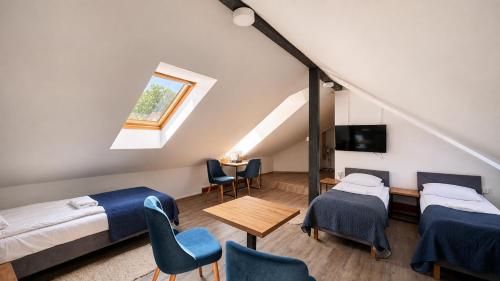 a room with two beds and a table and chairs at Hotel Ukiel Wellness & SPA in Olsztyn