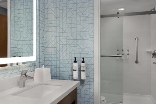 a bathroom with a sink and a shower with two bottles of wine at Homewood Suites Mobile in Mobile