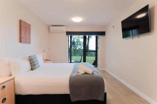 a bedroom with a bed with a stuffed animal on a stool at Comfort Resort Leura Gardens in Leura