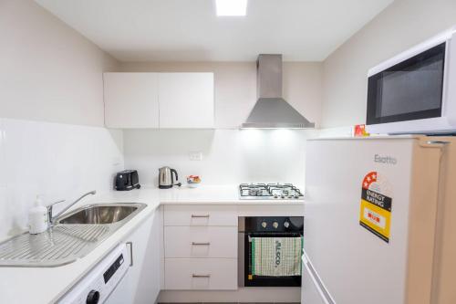 a white kitchen with a sink and a refrigerator at Comfort Resort Leura Gardens in Leura