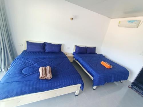two beds in a room with blue sheets and towels at Vital Point Kampot in Kampot