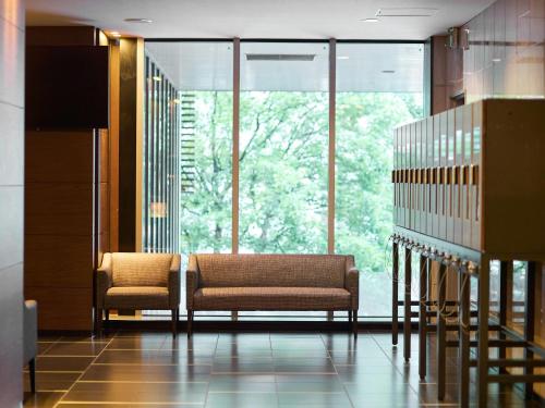 a lobby with two chairs and a large window at Comfort Hotel Sendai West in Sendai