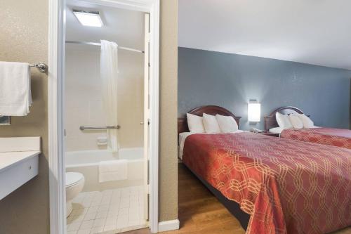 a hotel room with a bed and a bathroom with a shower at Econo Lodge Thomaston in Thomaston