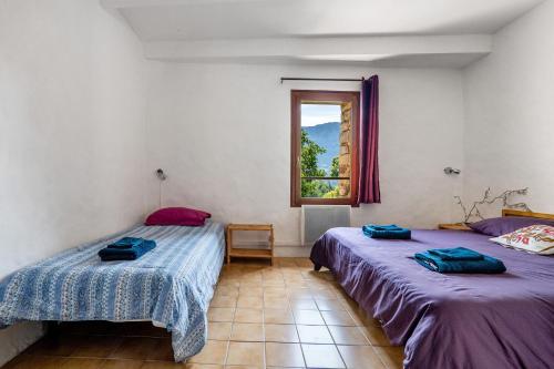 two beds in a room with a window at Gite La Chambrette in Blieux
