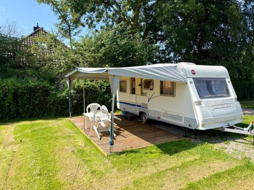 a white rv with a tent on a deck at Campinplatz Margarethenruh in Nordstrand