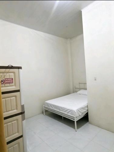 a small bedroom with a bed and a dresser at Hotel O Teratays Homestay in Banda Aceh