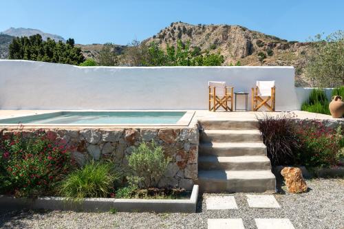 a house with two chairs and a swimming pool at Ktima Natura in Archangelos