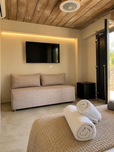 a living room with a couch and a flat screen tv at Pefkon Suites in Afitos