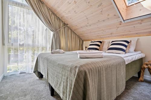 a bedroom with a bed with a wooden ceiling at Tago Forest - Dune Apartments in Jūrmalciems