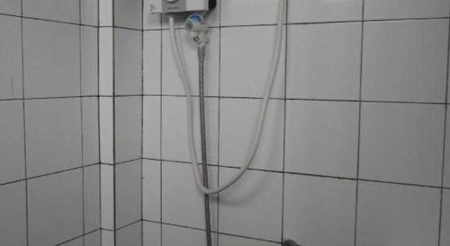 a shower with a hose attached to a white tiled wall at 41Studio in Nakhon Phanom