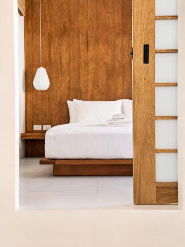 a bedroom with a bed and a wooden wall at Haku - Japandi Village in General Luna