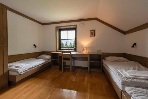 a room with two beds and a desk and a window at Karami Mountainhouse in Tržič