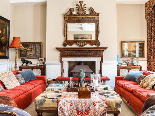 a living room with red couches and a fireplace at Kyre Park in Tenbury