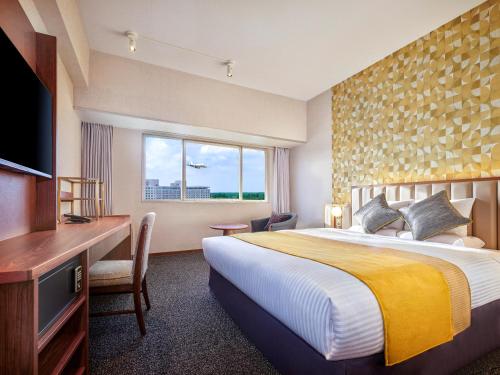 a hotel room with a bed and a desk and a television at Art Hotel Narita in Narita
