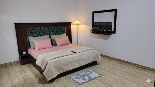 a bedroom with a bed with pink pillows and a mirror at CeylonAirbnb in Puttalam