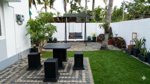 a patio with a black table and chairs in a yard at CeylonAirbnb in Puttalam