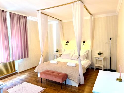 ein Schlafzimmer mit einem Himmelbett mit einem rosa Stuhl in der Unterkunft Cozy Hideout - Condo Hotel in Timişoara