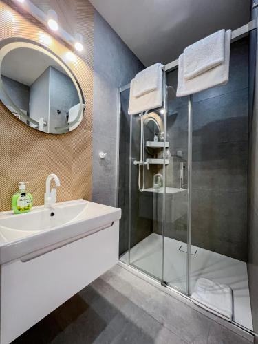 a bathroom with a sink and a shower with a mirror at VENETIA-Rooms in Biecz