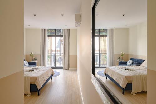 two beds in a large room with windows at Amazing Studio Boutique Hotel in Hanoi
