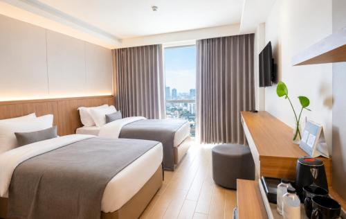a hotel room with two beds and a television at Shambhala Hotel Pattaya in Pattaya