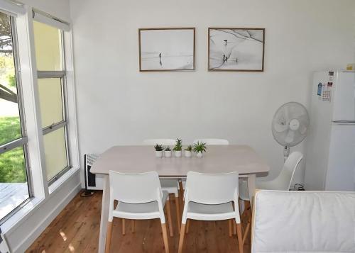 a white dining room with a white table and chairs at Barefoot Bungalow in Tomakin