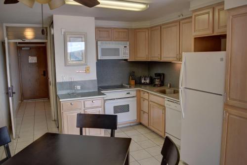 a kitchen with wooden cabinets and a white refrigerator at Mana Kai 710C in Wailea