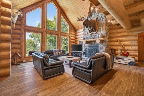 a living room with couches and a fireplace in a log cabin at Fiddler Lake Resort - Moose 93 in Mille-Isles