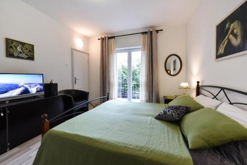 - une chambre avec un grand lit vert et une télévision à écran plat dans l'établissement Apartments Dado, à Zadar