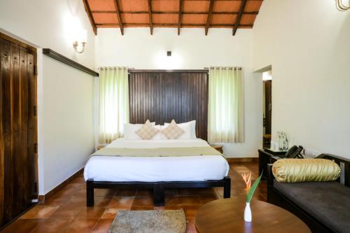 a hotel room with a bed and a couch at Kadkani River Resort Coorg in Siddapur