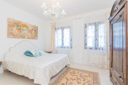 a white bedroom with a bed and a chandelier at Berto's house tra mare e laguna in Cavallino-Treporti