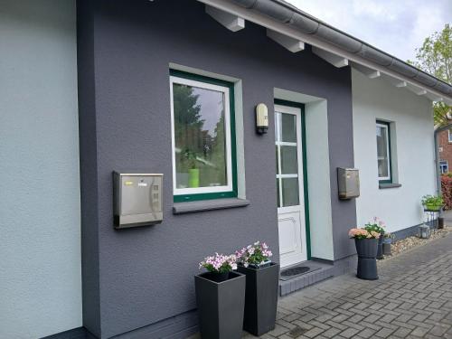 a house with two flower pots and a window at Ferienwohnung Auszeit mit Waldgeflüster 35231 in Hesel