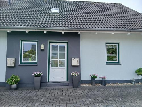 a blue house with a white door and potted plants at Ferienwohnung Auszeit mit Waldgeflüster 35231 in Hesel