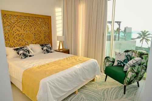 a bedroom with a bed and a chair and a window at Ocean Point Beachfront Penthouses by Gerards & Angel in Pointe aux Piments