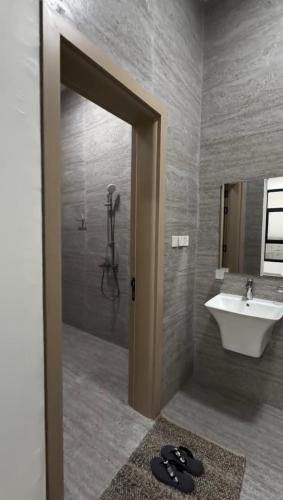 a bathroom with a sink and a shower and a mirror at دوحة ظُفار للعقارات in Sumhuran