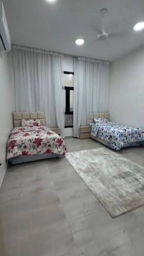 a bedroom with two beds and a rug at دوحة ظُفار للعقارات in Sumhuran