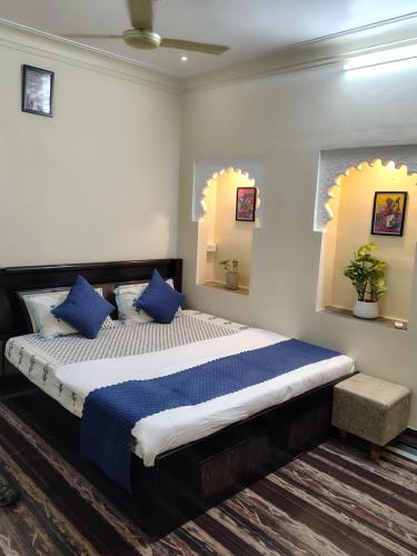 a bedroom with a large bed with blue pillows at Mahadev Bhavan in Chittaurgarh