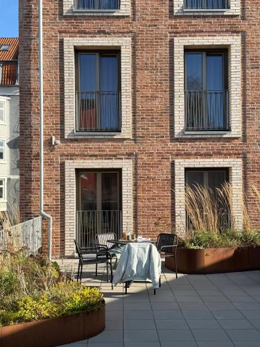 a patio with a table and chairs in front of a brick building at Aura Apartment Hotel in Aarhus