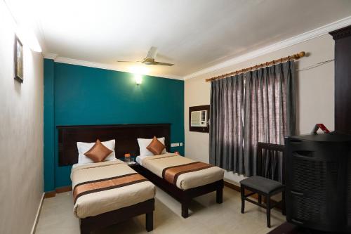 a bedroom with two beds and a blue wall at FabHotel City Inn in Hyderabad