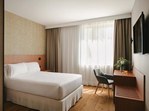 a hotel room with a bed and a desk at Sercotel Valladolid in Valladolid