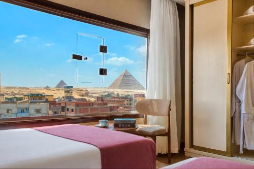 a bedroom with a view of the pyramids from a window at Premium Pyramids BoutiQue With Rooftop Access in Cairo